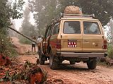 Manaslu 01 01 Landcruiser Stopped By A Tree On The Road We left Kathmandu in the dark at 5:15 and drove past people walking, bicycling and even jogging. At 6am we crested the lip of the valley and left Kathmandu behind. We continued west along the paved Prithvi Highway passing the ubiquitous Tata trucks and buses. We left the highway at 7:30 and drove 17km on a paved road to Dhading Besi, turned left and followed the unpaved road up through the early morning clouds. A small traffic jam occurred when a large tree fell across the road and had to be cut by one of the local young men.